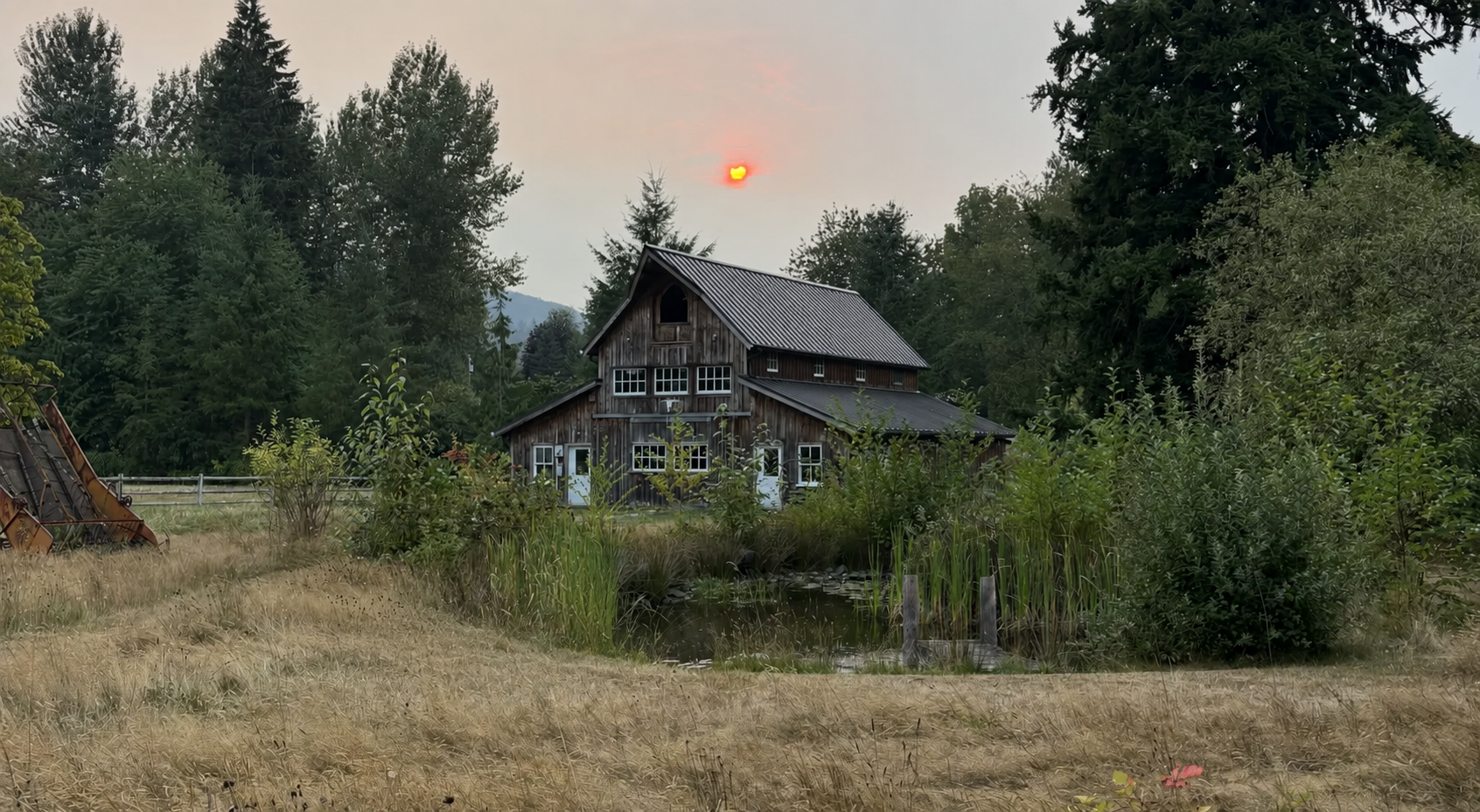 Rustic barn at sunset surrounded by trees and pasture